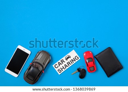 Car sharing concept. Composition with driver's license, vehicle key, toy cars, text sign "CAR SHARING" on blue background. Top view. Taxi alternative, temporary car rental, sharing economy