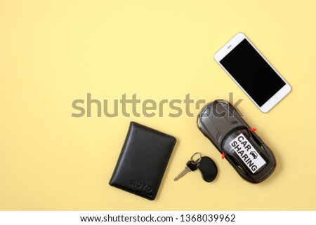 Carsharing concept. Toy car, car key, smart phone and driver license on yellow background. Minimal flat lay style composition, top view, copy space. Banner mockup for car rental agency.