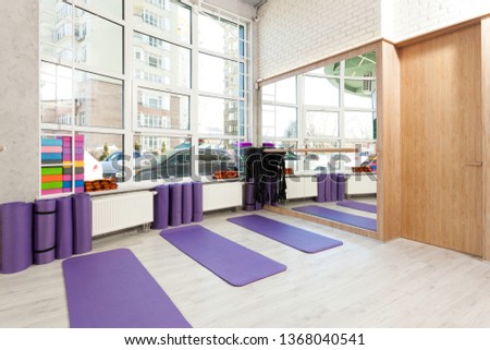 Empty space in fitness center, white brick walls, natural wooden floor and big windows, modern loft studio, yoga mats, comfortable open area for sport and exercises