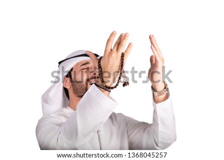 Arab Muslim young man holding masbaha and doing Duaa to God,
islamic emotions concept.
