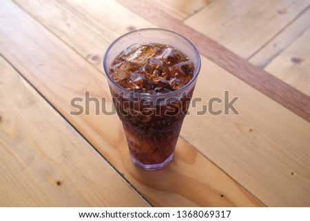 Cola glass with ice cubes placed on a wooden table