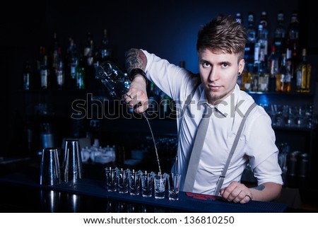 Bartender bartender is pouring a drink and looking at the camera Royalty-Free Stock Photo #136810250