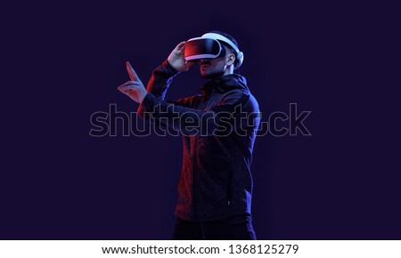 Model young man with beard in glasses of virtual reality on dark background.. Augmented reality, science, future technology concept. VR. Futuristic 3d glasses with virtual projection. Neon light.