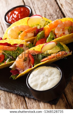 Corn tacos with shrimps, fresh vegetables and sauces close-up on the table. vertical
