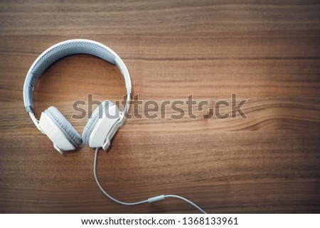 top view of white headphone on vintage wooden desk using for background