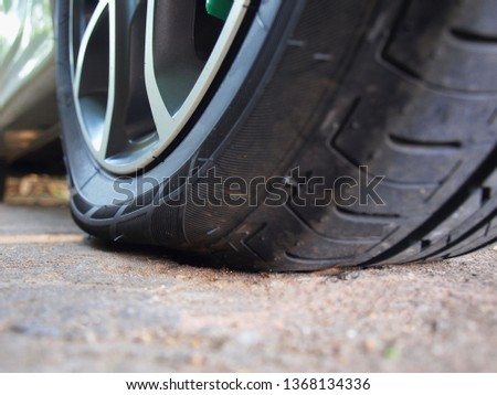 Flat or leaky tires: Damaged rear wheels in the parking lot On the background of the cement yard. Selective focus.