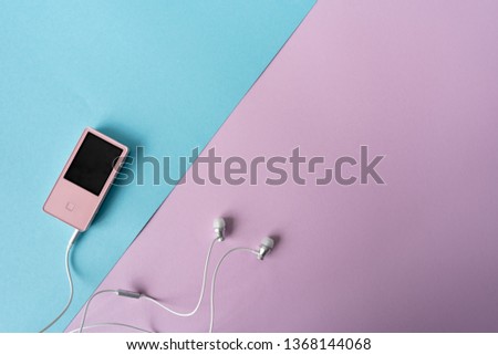 Top view. Portable music pink player and earphones on a purple and blue background. Place for text