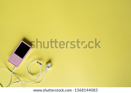 Top view. Portable music pink player and earphones on a yellow background. Place for text