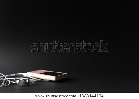 Portable music pink player and earphones on a black background. Place for text