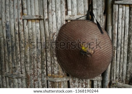 "capping" Traditional hats made of woven bamboo, hanging from a bamboo fence