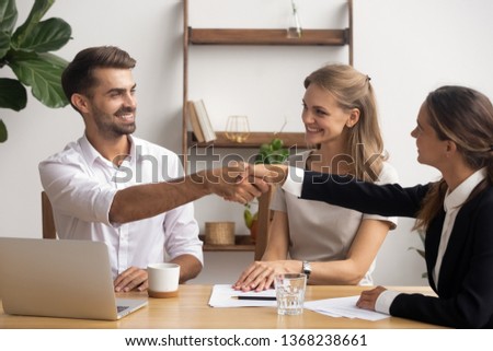 Happy employees handshake at corporate meeting welcoming new team member, male company manager and female client shake hands make business deal showing respect thanking for teamwork help in office