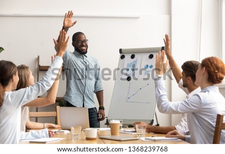 Business team voting concept, smiling african coach leader and diverse employees group raise hands up engaged in volunteering making unanimous decision participate in corporate presentation training Royalty-Free Stock Photo #1368239768