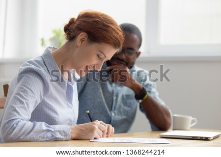 Happy female caucasian client customer hired employee signing contract meeting african american manager broker lawyer making insurance bank loan services commercial business deal write signature Royalty-Free Stock Photo #1368244214