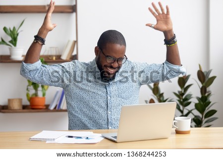Euphoric overjoyed african black businessman happy to read great online news get promoted rewarded celebrating business success bet bid win, excited with good work results feeling motivated winner Royalty-Free Stock Photo #1368244253