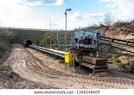 A string of transport belting in a  gravel pit for transporting gravel and sand over long distances, the belts go under of the road.
