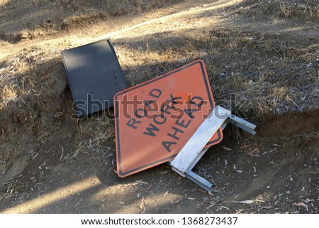 A disregarded, fallen road work warning sign set