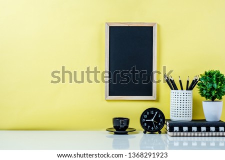 Front view of minimal workspace desk with supplies, and yellow wall.Copy space for product display montage