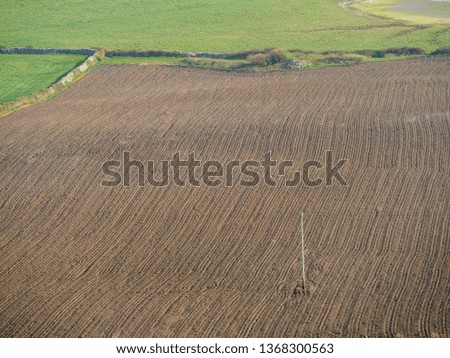 Freshly ploughed soil, next to green grass field, Agriculture, farming.