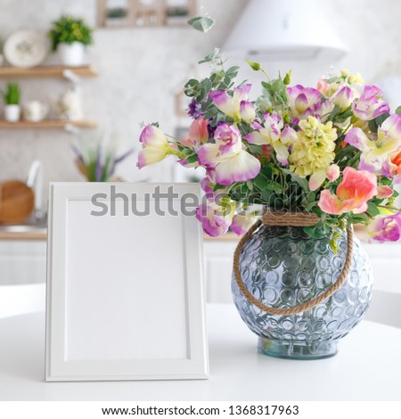 Wooden decorative frame on a white table with a bouquet of flowers.