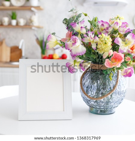 Wooden decorative frame on a white table with a bouquet of flowers.