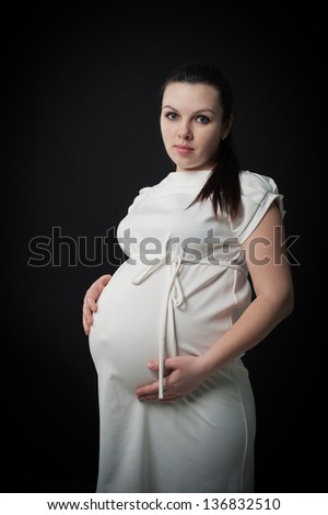 Pregnant woman with the beautiful belly isolated on black background.