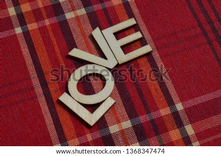 The word Love written in wooden letters on a red cloth background