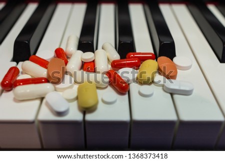 Pills on the piano keyboard. Concept of music and health.