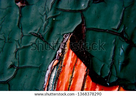 Cracked and warped layered green and orange paint on wood