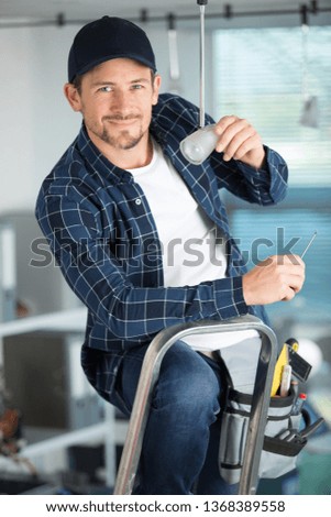 confident man fixing light at home