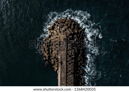 aerial photography in dark tones of waves breaking on the breakwater in Luarca