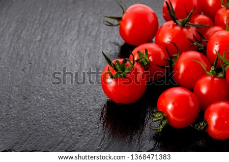 Fresh red cherry tomatoes on black stone plate