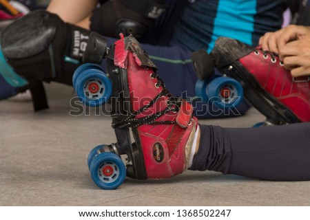 
Hands tying red and blue skates in the roller derby tournament