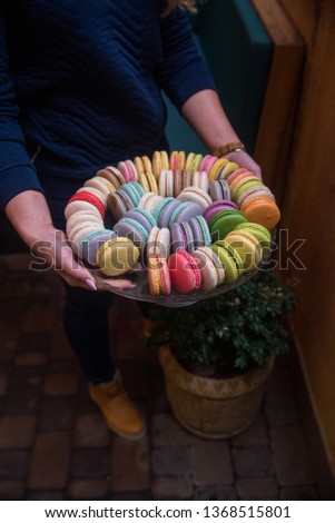Girl holding a big plate with macaroons, a big variety of macaroons. Sweets photography.
