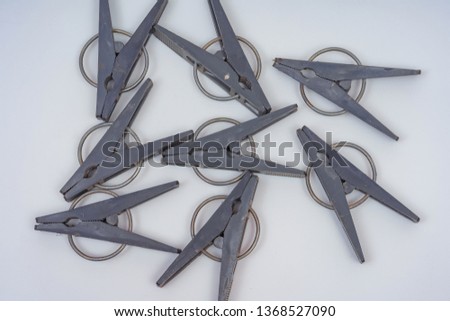 Black plastic clothes pegs on a white background. Clothespins for drying clothes. Pattern of gray clothespins on a light background.