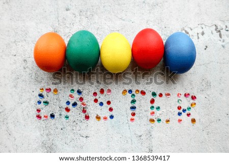 Five colorful easter eggs on wooden background with the word Easter is laid out with rhinestones