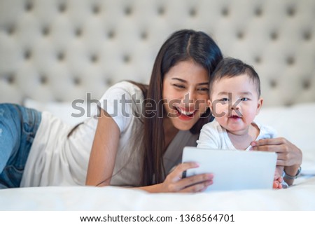 Mother and baby waching a cartoon in computer tablet on the bed