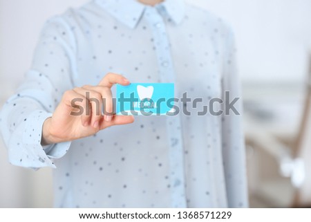 Woman holding business card indoors, closeup. Dental medical service