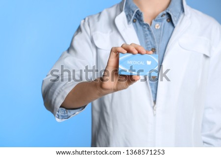 Doctor holding business card on color background, closeup with space for text. Dental medical service