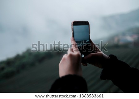 An asian woman using panorama function in smart phone to take a panoramic photo of rice terrace