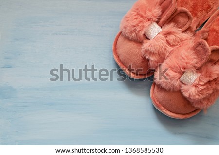 Cute fluffy slippers in the shape of a bunny with ears on a blue background.