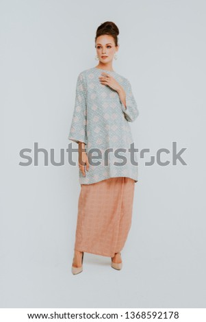 Beautiful caucasian female model wearing Baju Kurung (Malay traditional dress) isolate over white background.
Asian Female dress for Eid ul Fitr celebration or formal event.