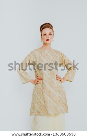 Beautiful caucasian female model wearing Baju Kurung (Malay traditional dress) isolate over white background.
Asian Female dress for Eid ul Fitr celebration or formal event.
