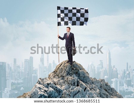 Successful businessman on the top of a city holding goal flag