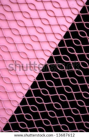 Metal grate over a pink wall and darkened opening