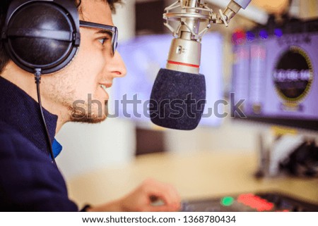 Young man in the broadcasting studio, radio, talking into the microphone