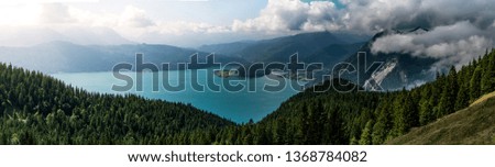 Mountain panorama with lake and forest and clouds