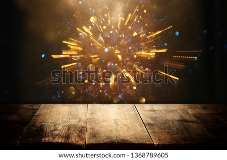 wooden table in front of glitter black and gold bokeh lights. For product presentation