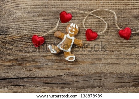 Gingerbread man and cute red hearts on wooden background. Copy space.