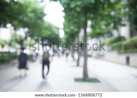 Blurred crowd of anonymous people walking on pedestrian with green tree both sides in the city, Seoul, Korea