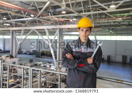 Portrait of young worker with wrench at CNC factory
